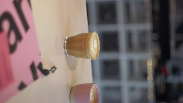 Vertical, glass cup with beautiful latte art flower in golden caramel coffee