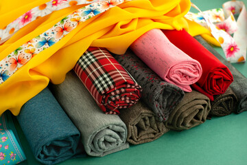 The fabric is folded into rolls. Fabric of different type and color for sewing clothes and...