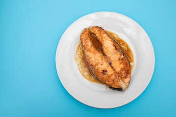 Fried salmon steak with sauce on white dish