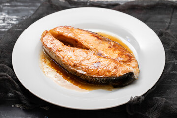 Fried salmon steak with sauce on white dish