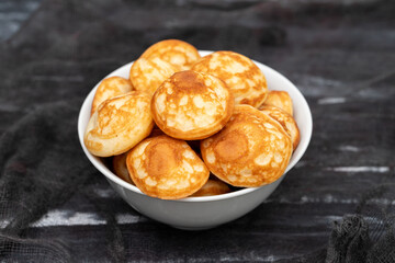 Heap of mini cereal pancakes in bowl on bright background.
