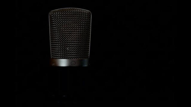 Studio condenser microphone with a large golden diaphragm on a dark background