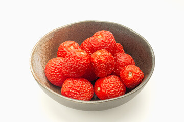 A pile of rotten tomatoes is on a bowl over a white background.