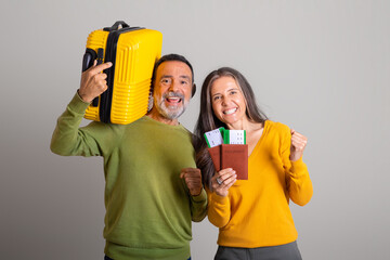 Happy excited caucasian elderly husband with suitcase and wife with tickets, passports making victory gesture