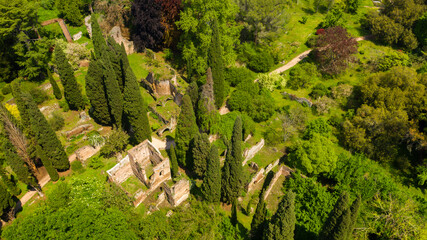 Aerial view of the ruins located in the garden of Ninfa, near Latina, Italy. The park is an Italian natural monument and contains exotic plants from various parts of the world. - obrazy, fototapety, plakaty