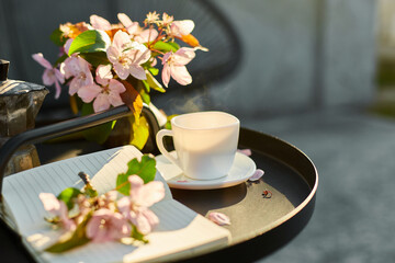 Cup of coffee flowers and notebook on the small black table