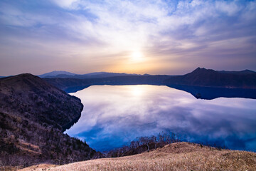 朝日の輝く空を湖面に映す山間の湖。北海道の摩周湖。 - obrazy, fototapety, plakaty