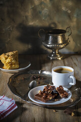 Milk chocolate with hazelnuts and a cup of coffee on a rustic table