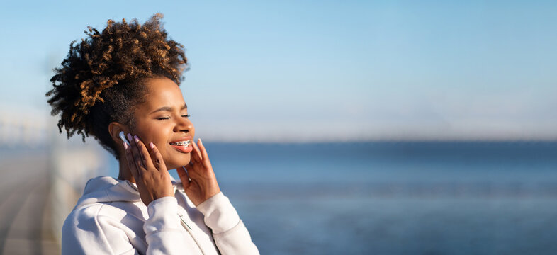 Young Black Female Enjoying Favorite Music In Wireless Earphones While Training Outdoors