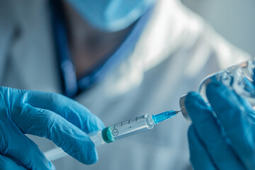 A medical professional in a chemical laboratory collects a dose of a drug ready to be administered to the patient using a syringe and needle. Shooting with a large pllan in a medical laboratory