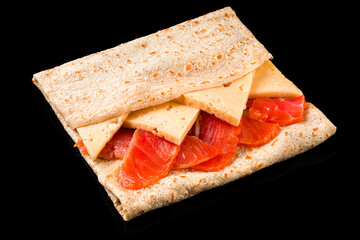 Fried thin pancakes with salmon fish and cheese on black background.