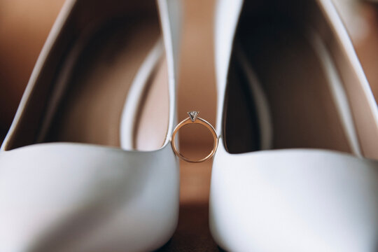 Wedding Details. The bride's wedding ring between white women's heeled shoes
