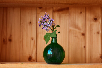 One vase with flowers at wooden background from side view