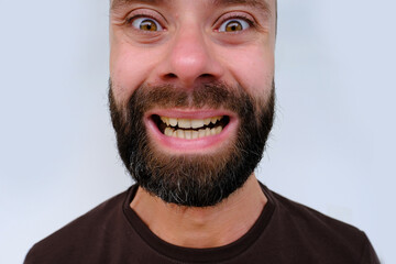 close-up male face makes negative grimaces aggression, young bearded man, senior 30 years old with...