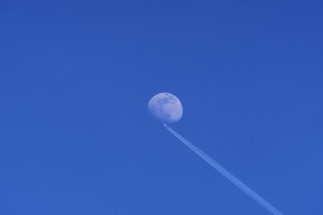 Samolot przelatujący na tle księżyca, błękitne niebo. - obrazy, fototapety, plakaty