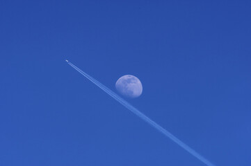 Samolot przelatujący na tle księżyca, błękitne niebo. - obrazy, fototapety, plakaty