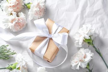 Gift box with white bow and flowers on crumpled paper background