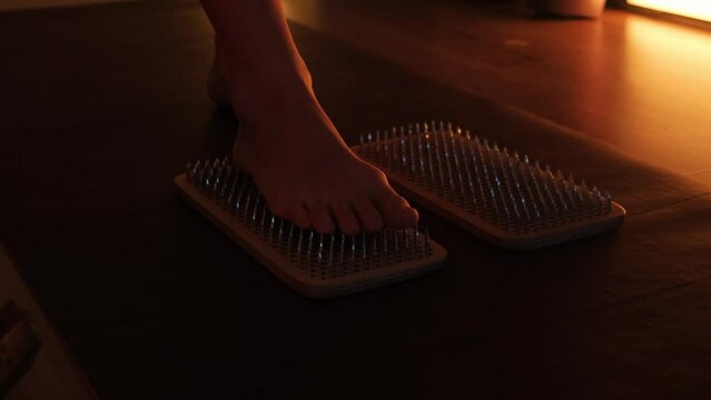 Women's feet stepping on sharp nails for meditation, sadhu wooden board. Yoga practice