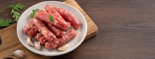 Raw Taiwanese sausage in garlic flavor in a plate on wooden table background.