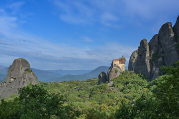 Rocky Meteora landscape with the Monastery of St. Nicholas Anapausas situated at the top of a cliff, famous tourism destination in Greece, mountains in the background under a blue sky, copy space