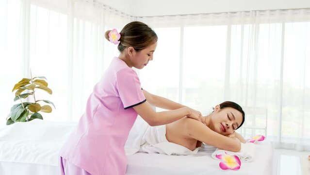 Relaxing young Asian woman lying down and closing her eyes on massage beds while receiving a massage from a therapist at an Asian luxury spa salon and a wellness center, waiting for Spa salon concept