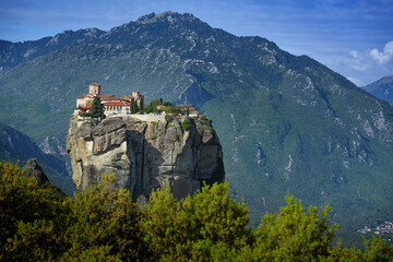 Naklejka premium Monastery of the Holy Trinity built on the top of a rock in the Meteora complex near Kalambaka, famous tourism attraction in Greece, mountain landscape in the background, blue sky, copy space
