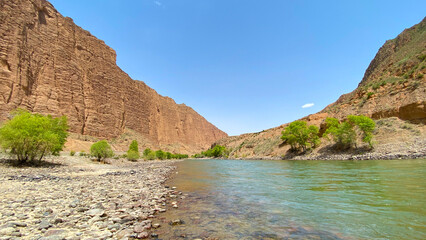 Panorama of an amazing canyon in Kyrgyzstan. A mountain river is visible. Rocky shore.