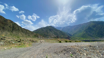 Fototapeta premium Mountain road. The amazing nature of Kyrgyzstan. Beautiful mountain landscape. Green hills, blue sky