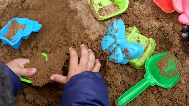 Close up hands of baby toddler playing in the sandbox