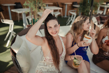 Stylish women drinking cocktails in the terrace of a pool