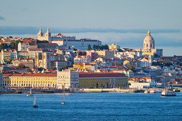View of Lisbon Alfama district with National Pantheon and Monastery of St. Vincent over Tagus river from Almada with yachts tourist boats on sunset. Lisbon, Portugal
