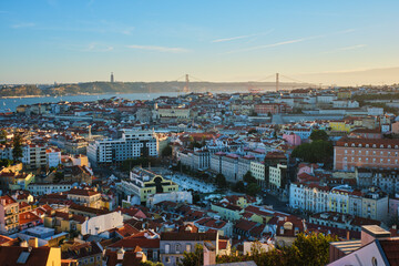 Naklejka premium View of Lisbon famous view from Miradouro da Senhora do Monte tourist viewpoint of Alfama and Mauraria old city district, 25th of April Bridge at sunset. Lisbon, Portugal