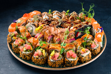 Assorted Japanese sushi roll set with salmon, tuna, shrimp, eel, avocado, cream cheese, cucumber and red caviar in a plate.