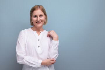 blond hair woman of mature years in a white shirt smiling on a studio background