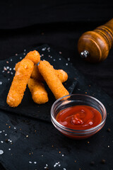 Snack breaded mozzarella cheese sticks with ketchup.