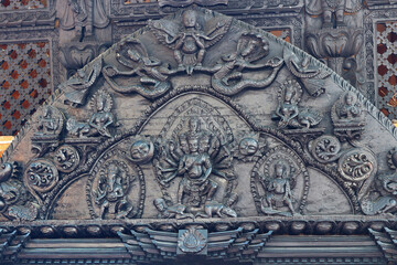 Decorative religious wood carving at a Hindu Kedareshwor temple in Pokhara, Nepal. Many-armed and many-headed Shiva surrounded by Nagas and demigods.