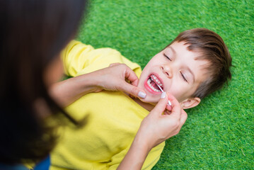 Woman speech therapist helps a child correct the violation of his speech in her office