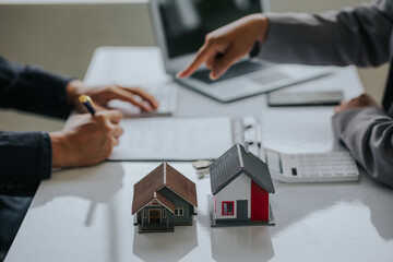 Fototapeta premium Businessman or real estate agent with house model laying down contract, having contract in place to protect it, signing little agreement form in office, keeping real estate, moving house or renting pr