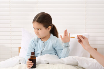 Daughter refusing to take cough syrup from her mother in bedroom