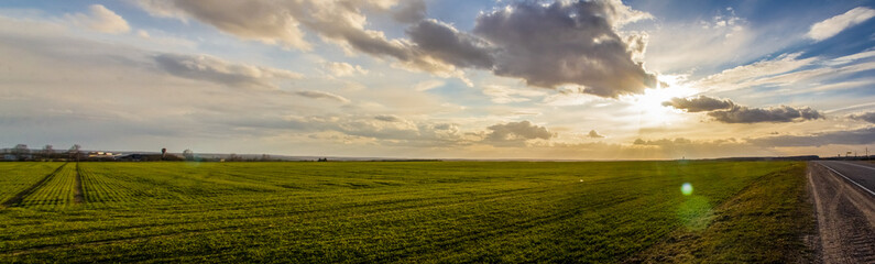 Panorama of beautiful thunderclouds over the field. Landscape at sunset. Cloudy sky banner.