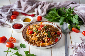 A hearty family lunch: buckwheat with vegetables stewed with spices and fresh herbs in a beautiful...