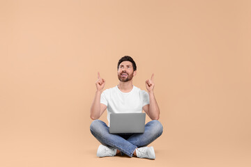 Happy man with laptop on beige background