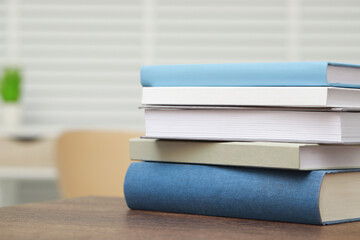 Stack of hardcover books on wooden table indoors. Space for text