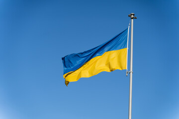 Blue-yellow Ukrainian flag flies against the background of clear blue sky