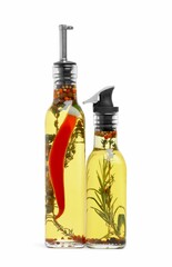 Glass bottles of cooking oils with spices and herbs on white background