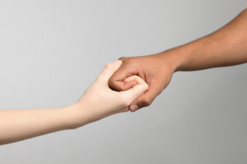 International relationships. People strongly joining hands on light grey background, closeup