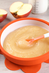 Healthy baby food. Bowl with delicious apple puree on white wooden table, closeup