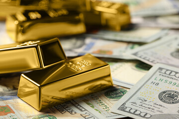 Shiny gold bars on dollar banknotes, closeup. Space for text
