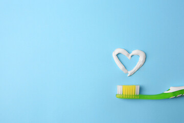 Heart made with toothpaste and brush on light blue background, top view. Space for text