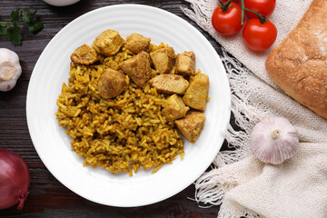 Delicious rice with chicken served on wooden table, flat lay